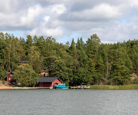 Punaisia rakennuksia meren rannalla Rymättylässä.