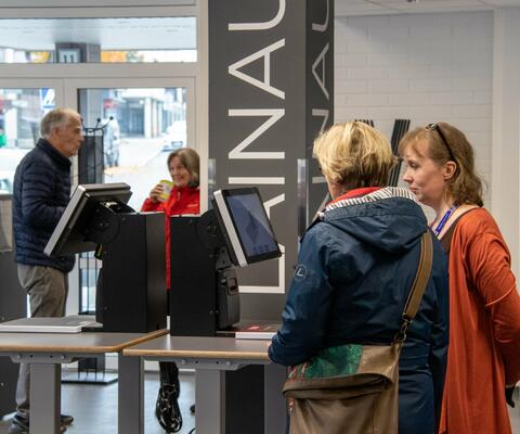 Naantalin pääkirjastossa kirjastovirkailija neuvoo lainauslaitteen kanssa. Kuva:Petra Saajanlehto