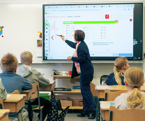 Opettaja opettamassa taulun edessä luokassa.