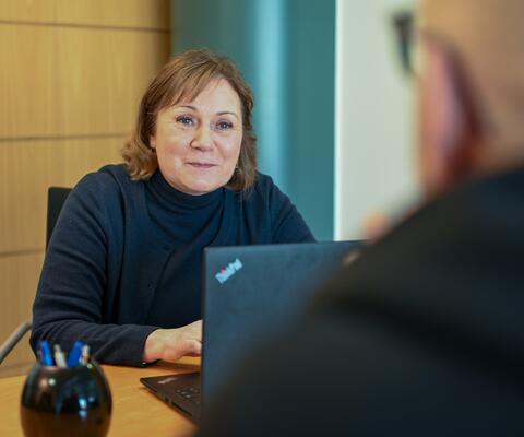 Nainen keskustelee vastapäätä istuvan asiakkaan kanssa pöydän ääressä.