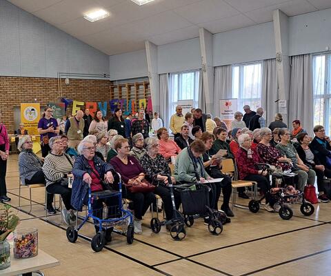 Ikäihmisiä messuilla istumassa urheilutalolla