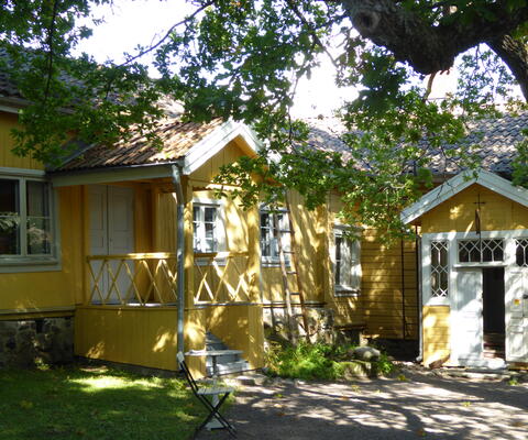 keltaiseksi maalattu puurakennus ja vehreä piha