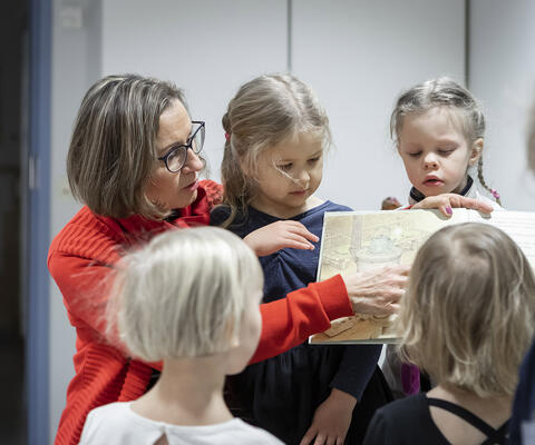 Varhaiskasvatuksen opettaja näyttää kirjaa lapsille.