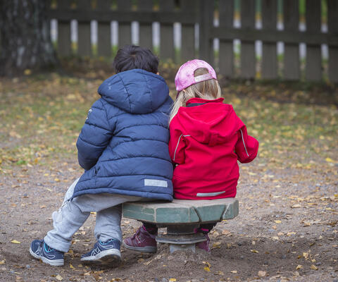 Kaksi lasta istuu puistossa.