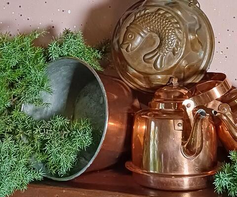 tasolla vanhoja kupariastioita ja katajan oksia