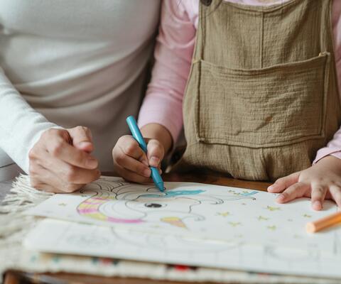 Äiti ja pieni lapsi värittävät värityskirjan kuvaa.