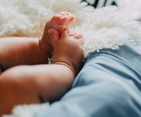 Vastasyntyneen vauvan kippurassa olevat jalat pehmeällä pedillä.