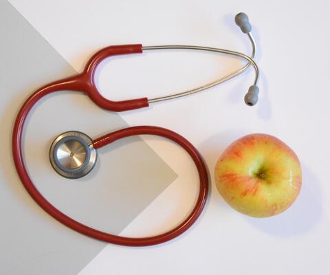 Stetoskooppi ja omena pöydällä