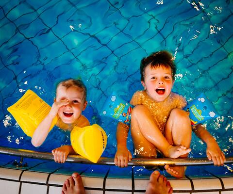 Pojat roikkuvat uima-altaan reunalla uimahallissa