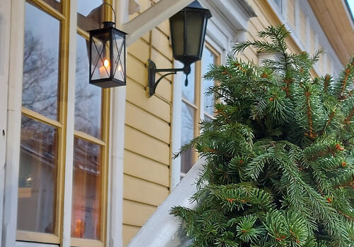 Havuköynnös museon porraskaiteella ja kynttilälyhty roikkuu museon ikkunan edessä.