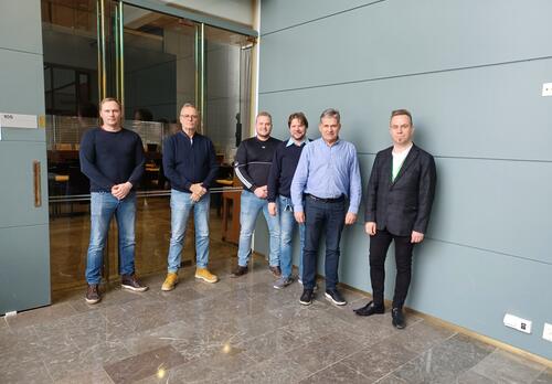 Kaupungintalon käytävällä kuusi miestä rivissä.