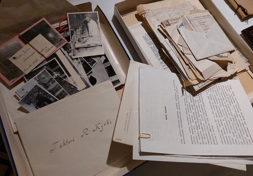 sekalaisia papereita ja mustavalkovalokuvia pöydällä