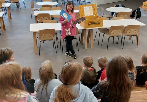 lapsia yleisönä katsomassa naista joka selostaa 