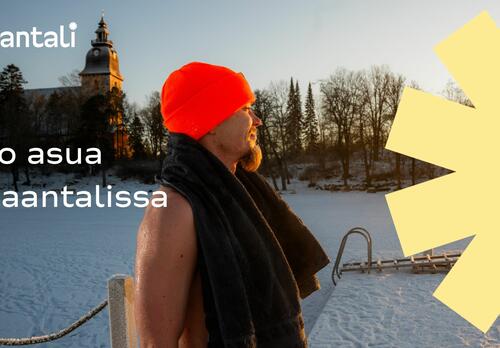 Mies nousee avannosta oranssi pipo päässä, Naantalin kirkko taustalla