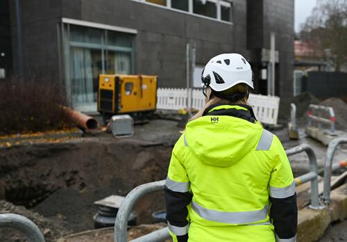 Työnjohtaja keltaisessa huomiotakissa valvoo työmaata Naantalissa. Taustalla kaupungintalo.