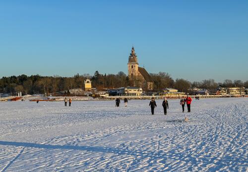 Kävelijöitä talvella merenjäällä Naantalin Vanhankaupungin edustalla.