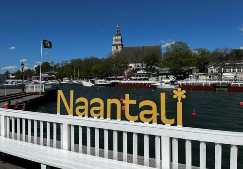 Naantalin rannassa keltaiset logon mukaiset Naantali-kohokirjaimet ja taustalla Naantalin kirkko.