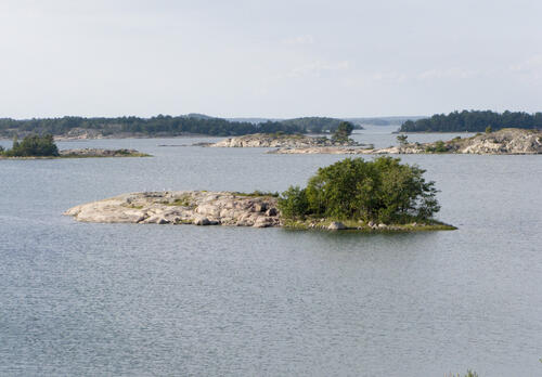 Kallioinen luoto meren keskellä, taustalla lisää luotoja.