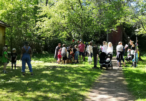 ihmisiä vehreässä puutarhassa kesäisenä päivänä