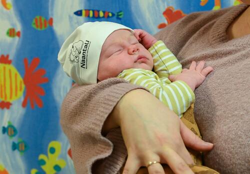 Vuoden 2025 ensimmäinen vauva Muumipipo päässä, äitinsä sylissä.