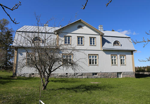 vaaleaksi maalattu puurakennus maisemassa