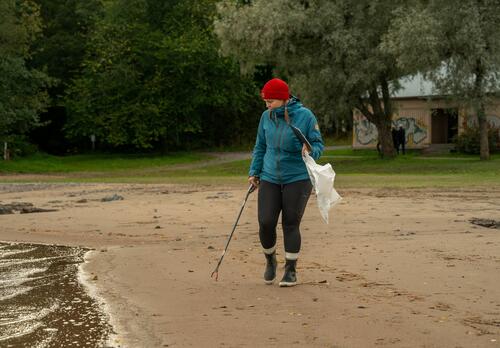Henkilö kerää roskia rannalla.