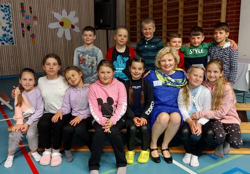 Ryhmäkuva ukrainalaisista oppilaista ja suurlähettiläs Olga Dibrovasta Karvetin koulun liikuntasalissa.