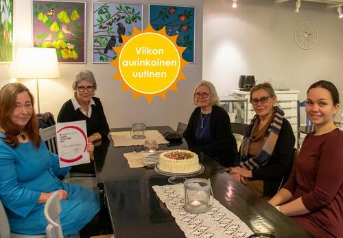 Kahvilan pöydän ympärillä istuu viisi naista katsoen kameraan. Siniseen mekkoon pukeutunut pitkähiuksinen nainen pitelee diplomia. Viikon aurinkoinen uutinen -logo.