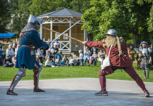 Keskiaikatapahtumassa kaksi haarniskaan puettua taistelijaa miekkailee.