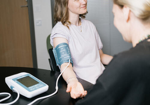 Naisen kädestä mitataan verenpainetta.