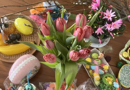 Tulppaaneja ja pääsiäiskoristeita pöydällä.