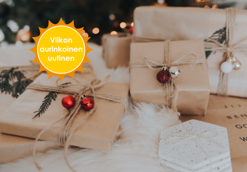 Yksiväriseen ruskeaan paperiin paketoituja, juutinnarulla ja punaisilla joulupalloilla koristeltuja lahjapaketteja kuusen alla. Viikon aurinkoinen uutinen-logo.