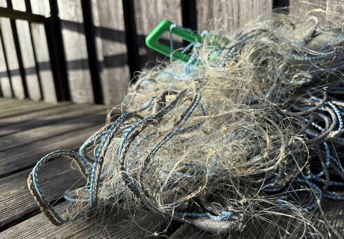 Rikkinäisiä kalaverkkoja sekaisessa kasassa laiturilla.