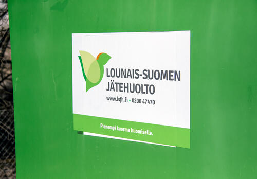 Vihreän jäteastian kyljessä on tarra, jossa lukee Lounais-Suomen Jätehuolto.