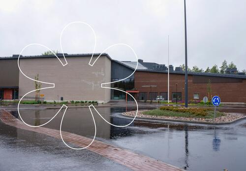 Luonnonmaan perhetalon vaaleanharmaa- ja punatiilinen uudisrakennus, kuvan päällä Onnellinen aurinko -elementti.