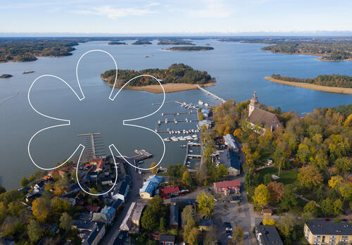 Syksyinen Naantalin Vanhakaupunki kuvattuna ilmasta. Kuvan päällä Onnellinen aurinko -elementti, joka muistuttaa kukkaa tai aurinkoa.