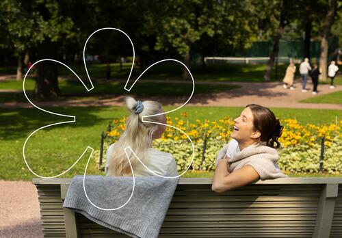 Nuoret naiset istuvat Kirkkopuiston penkillä. Kuvassa Onnellinen aurinko -elementti.