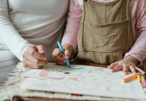 Äiti ja pieni lapsi värittävät värityskirjan kuvaa.