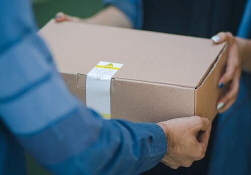 Henkilö ohjentaa toiselle postipakettia.