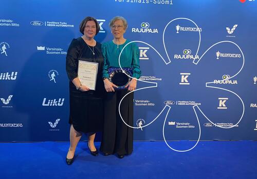 Susanne Nummelin ja Maija Puolakanaho pitelevät palkintodiplomia ja -lautasta. Onnellinen aurinko -elementti.