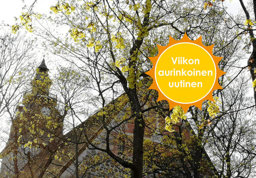 Naantalin kirkko alhaalta kuvattuna, taivasta vasten. Kirkon edessä on puu, johon on muodostumassa lehtiä. Viikon aurinkoinen uutinen -logo.