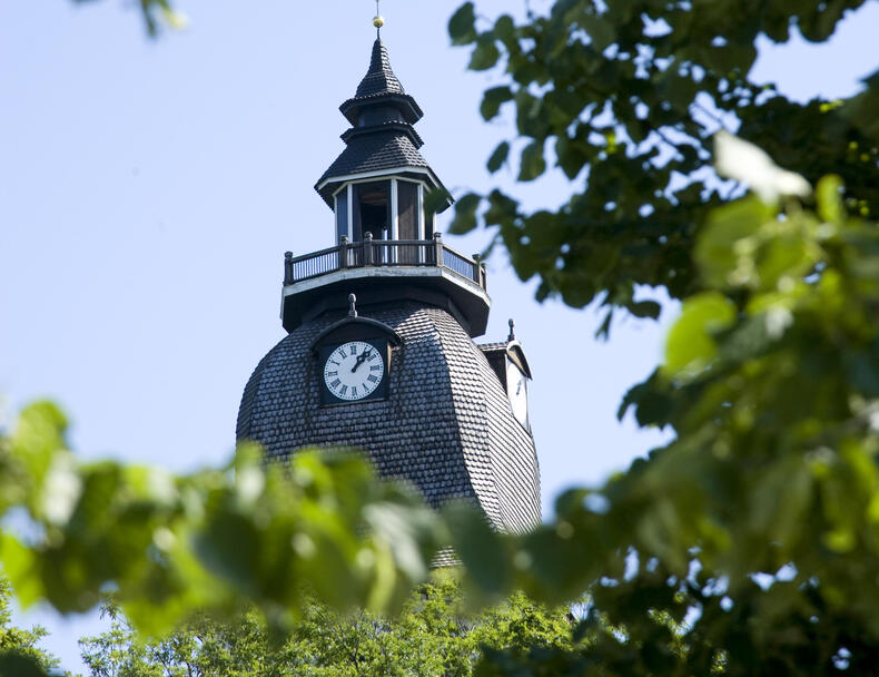 Naantalin kirkon torni kesällä puiden välistä kuvattuna.