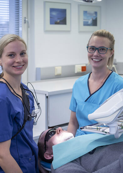 Hammaslääkäri ja hammashoitaja hymyilevät