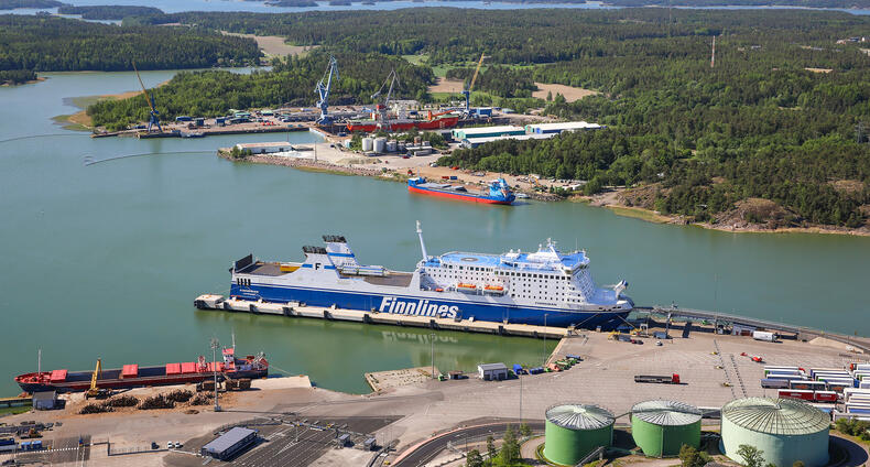 Finnlinesin alus on Naantalin satamassa, taustalla avautuu meren lahti ja vastarannalla näkyy korjaustelakka ja metsää.
