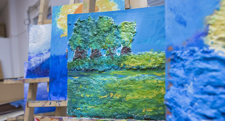 Värikkäitä maalauksia maalaustelineissä.