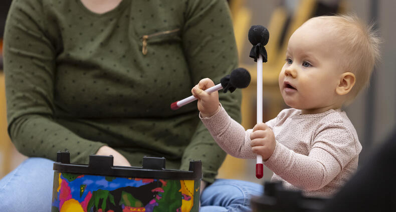 Vauva pitelee rumpupalikoita ja vanhempi istuu vieressä.
